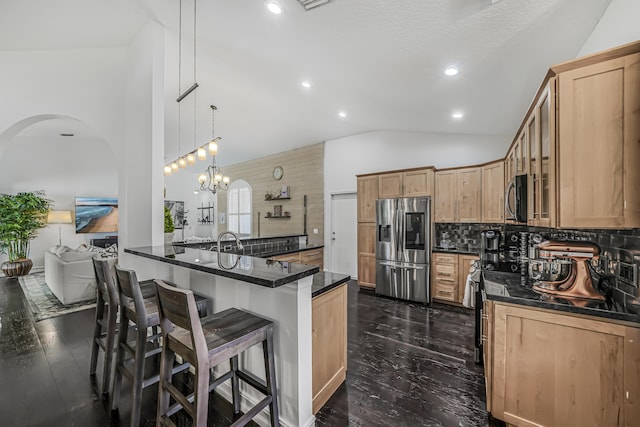 kitchen with tasteful backsplash, arched walkways, lofted ceiling, appliances with stainless steel finishes, and a breakfast bar area