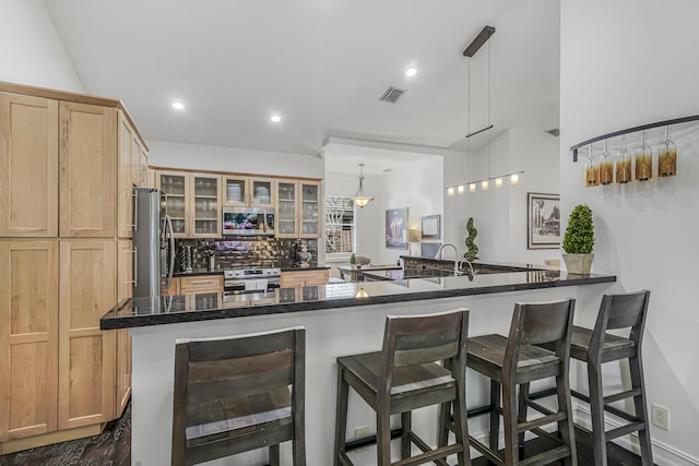 kitchen with a breakfast bar, tasteful backsplash, visible vents, and stainless steel appliances