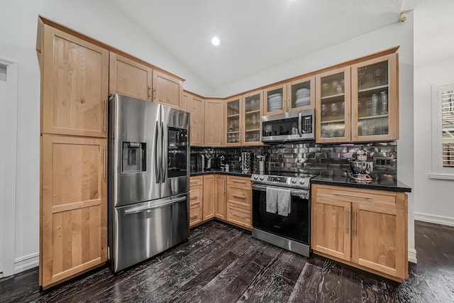 kitchen with lofted ceiling, appliances with stainless steel finishes, dark countertops, and decorative backsplash