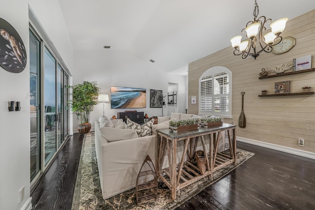 living area with lofted ceiling, a notable chandelier, wood walls, wood finished floors, and baseboards