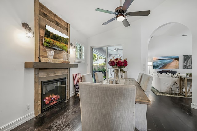 dining space with a fireplace, dark wood finished floors, lofted ceiling, ceiling fan, and baseboards