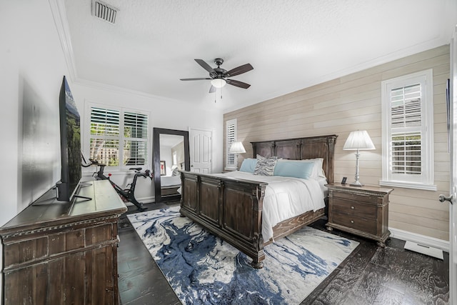 bedroom with wooden walls, baseboards, visible vents, ornamental molding, and a textured ceiling