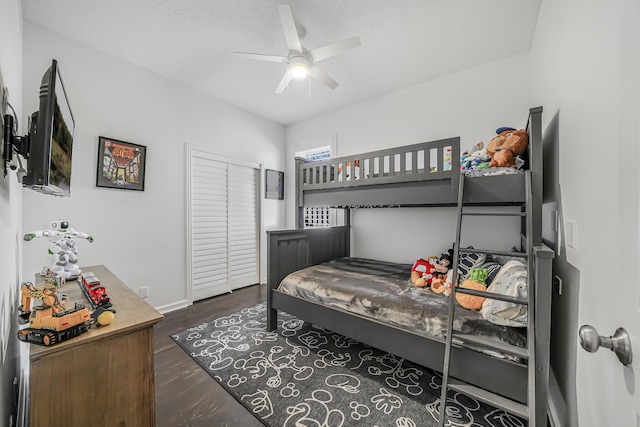 bedroom with baseboards, dark wood finished floors, a ceiling fan, a textured ceiling, and a closet