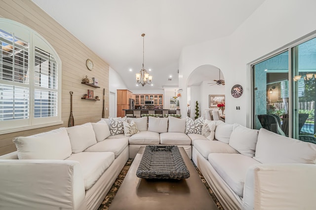 living area with a wealth of natural light, arched walkways, lofted ceiling, and wooden walls