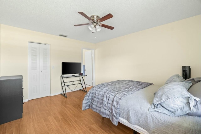 bedroom with visible vents, a ceiling fan, wood finished floors, a textured ceiling, and a closet