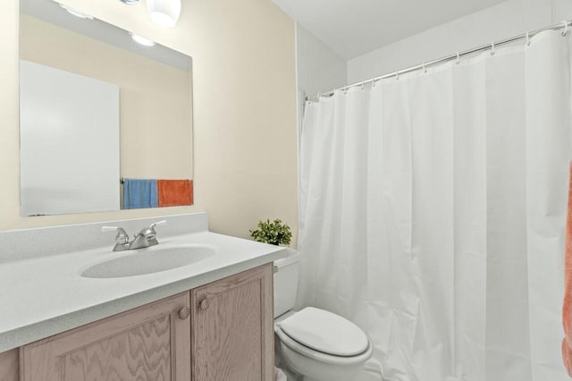 full bathroom featuring a shower with shower curtain, vanity, and toilet