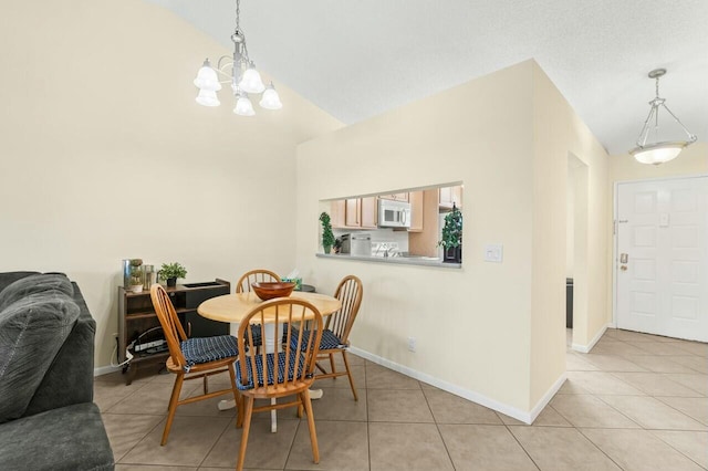 dining space with lofted ceiling, an inviting chandelier, baseboards, and light tile patterned flooring