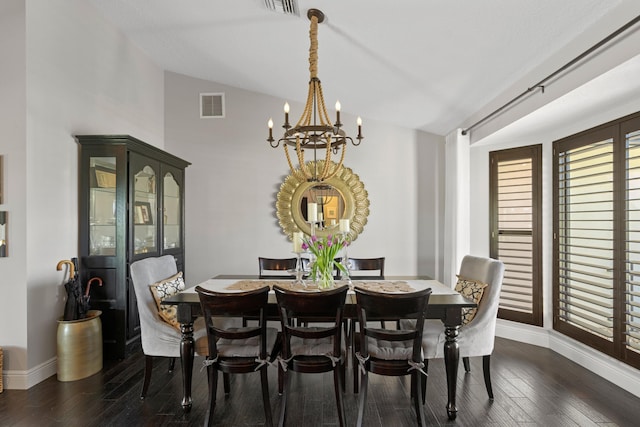 dining room featuring dark wood-type flooring, vaulted ceiling, and a notable chandelier