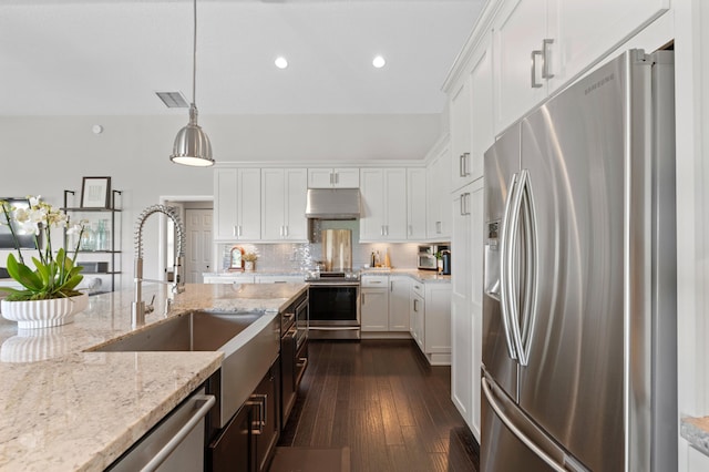 kitchen with pendant lighting, white cabinetry, appliances with stainless steel finishes, and light stone counters