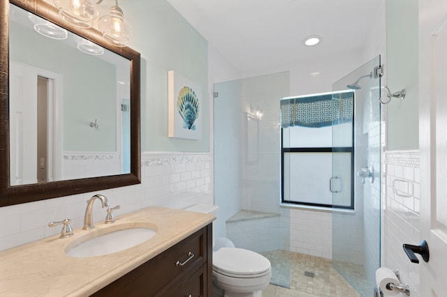 bathroom featuring vanity, a shower with door, tile walls, and toilet