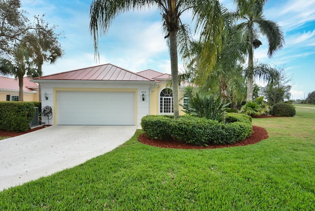 view of front of home featuring metal roof, an attached garage, driveway, stucco siding, and a front lawn