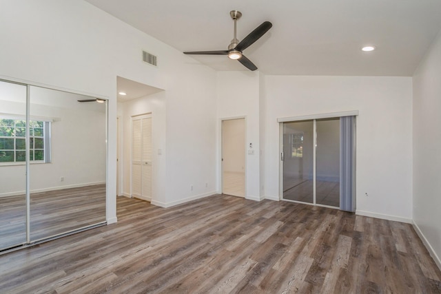 unfurnished bedroom with dark hardwood / wood-style flooring, two closets, high vaulted ceiling, and ceiling fan