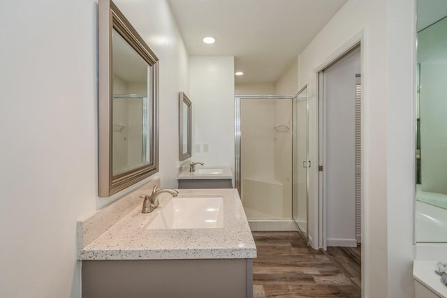 bathroom with wood-type flooring, a shower with door, and vanity