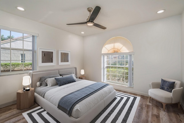 bedroom with multiple windows, wood-type flooring, and ceiling fan