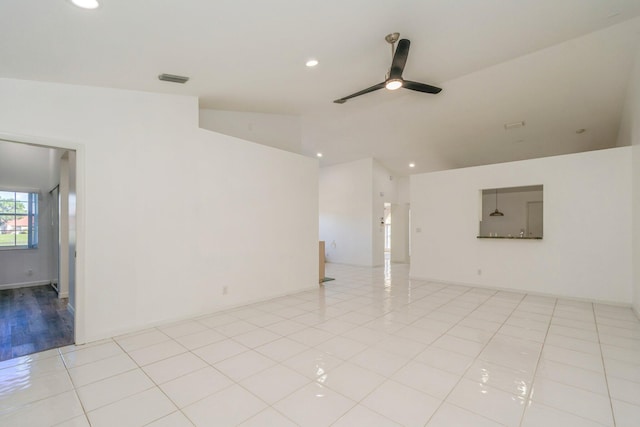 tiled empty room featuring vaulted ceiling and ceiling fan