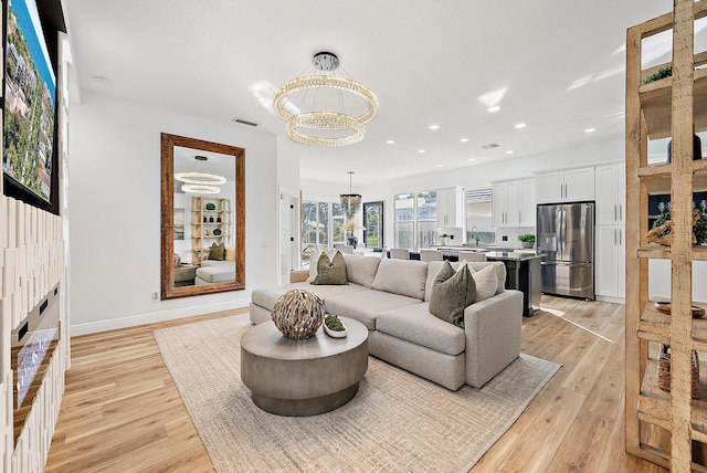 living room with sink, an inviting chandelier, and light hardwood / wood-style floors