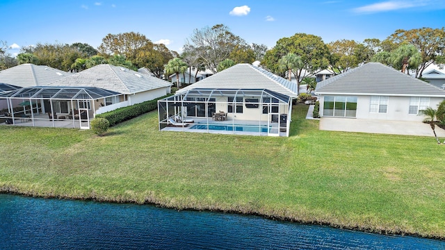 back of property with a lanai, a lawn, and a water view