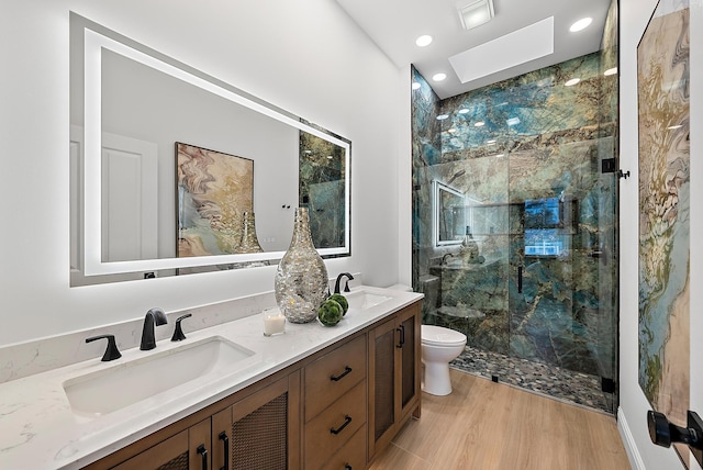 bathroom with hardwood / wood-style floors, a skylight, vanity, toilet, and walk in shower