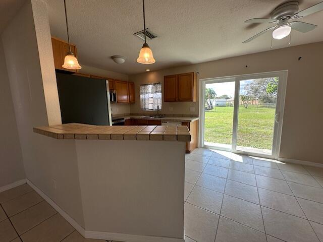 kitchen with decorative light fixtures, sink, stainless steel fridge, and kitchen peninsula