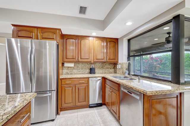 kitchen featuring light tile patterned flooring, tasteful backsplash, sink, stainless steel appliances, and light stone countertops