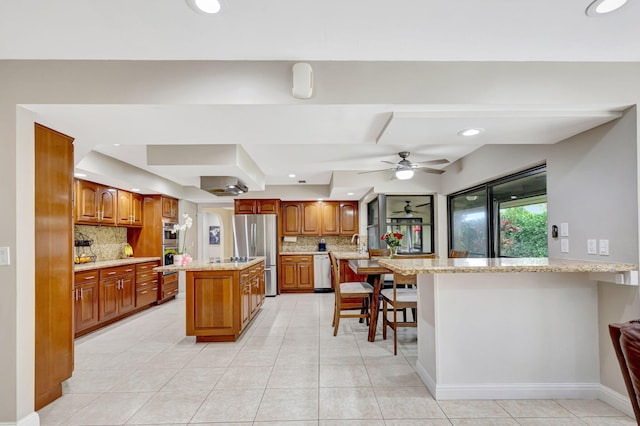 kitchen with a kitchen breakfast bar, stainless steel appliances, light stone counters, a kitchen island, and kitchen peninsula