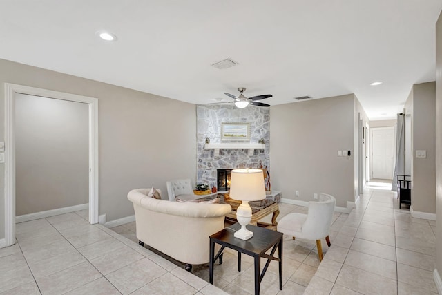 tiled living room featuring a fireplace and ceiling fan