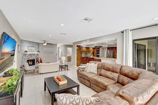 tiled living room featuring ceiling fan and a fireplace