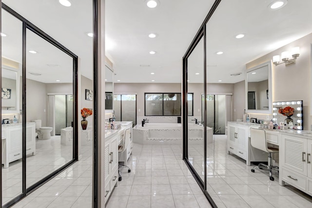 bathroom featuring a relaxing tiled tub, vanity, tile patterned flooring, and toilet