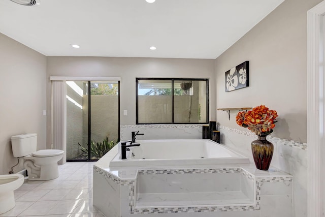 bathroom featuring a bidet, toilet, tile patterned flooring, and tiled tub