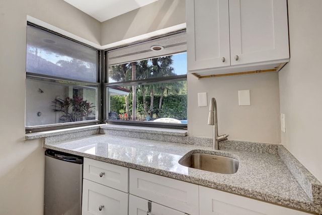 kitchen with light stone countertops, sink, white cabinets, and refrigerator