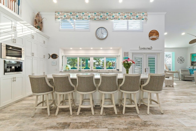 2666 SE Erickson Dr, Port Saint Lucie, FL 34984 - kitchen featuring white cabinets, black oven, a breakfast bar area, and a large island with sink