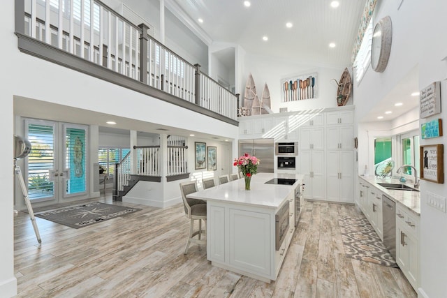 2666 SE Erickson Dr, Port Saint Lucie, FL 34984 - kitchen with a large island, sink, a breakfast bar, appliances with stainless steel finishes, and white cabinets