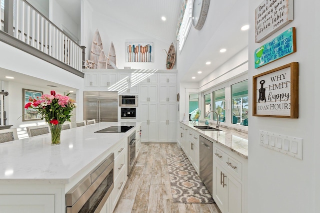 2666 SE Erickson Dr, Port Saint Lucie, FL 34984 - kitchen with sink, white cabinetry, light stone counters, built in appliances, and a large island