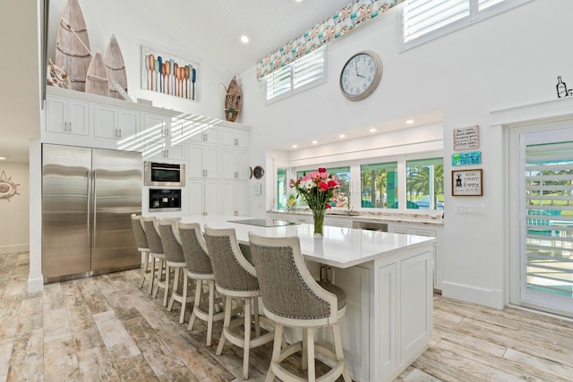 2666 SE Erickson Dr, Port Saint Lucie, FL 34984 - kitchen featuring white cabinetry, a kitchen bar, built in refrigerator, a center island, and light hardwood / wood-style flooring