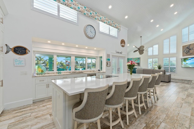 2666 SE Erickson Dr, Port Saint Lucie, FL 34984 - kitchen with a spacious island, light wood-type flooring, a kitchen breakfast bar, white cabinets, and a high ceiling
