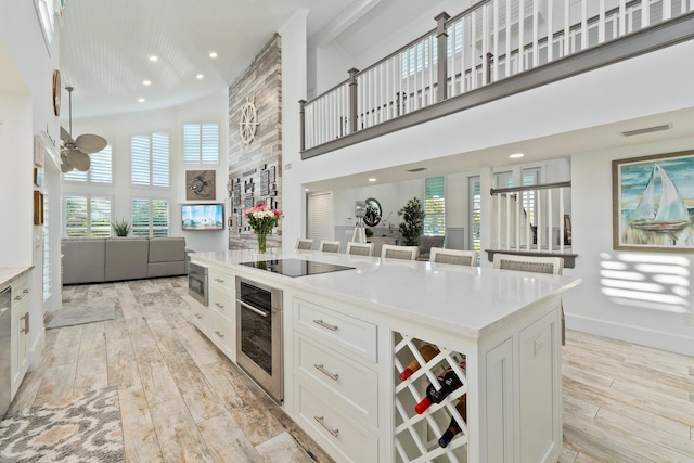 2666 SE Erickson Dr, Port Saint Lucie, FL 34984 - kitchen featuring white cabinetry, stainless steel appliances, a center island, a high ceiling, and light hardwood / wood-style floors