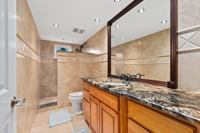 2666 SE Erickson Dr, Port Saint Lucie, FL 34984 - bathroom featuring vanity, tiled shower, tile walls, and toilet