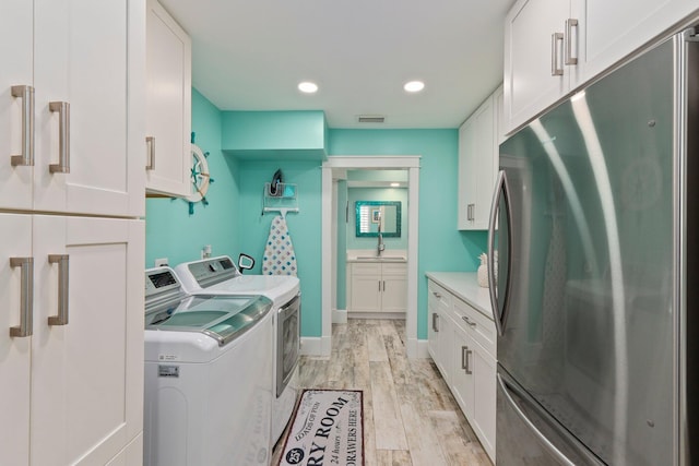 2666 SE Erickson Dr, Port Saint Lucie, FL 34984 - washroom featuring cabinets, separate washer and dryer, sink, and light hardwood / wood-style floors