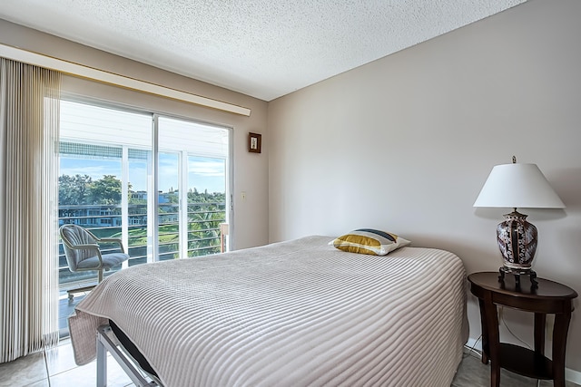 bedroom with access to exterior, light tile patterned floors, and a textured ceiling