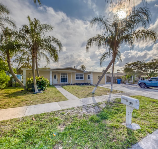 single story home featuring driveway, a front lawn, and stucco siding