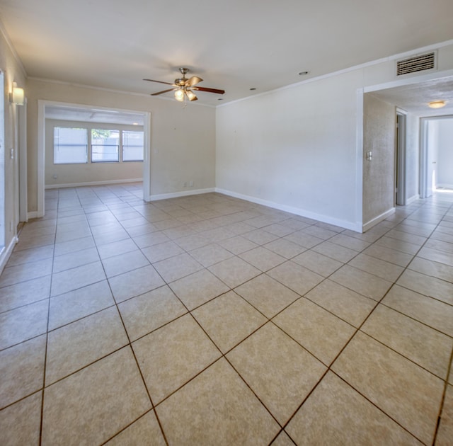 empty room with ornamental molding, a ceiling fan, visible vents, and light tile patterned floors