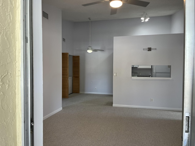 carpeted empty room with visible vents, high vaulted ceiling, a ceiling fan, and baseboards