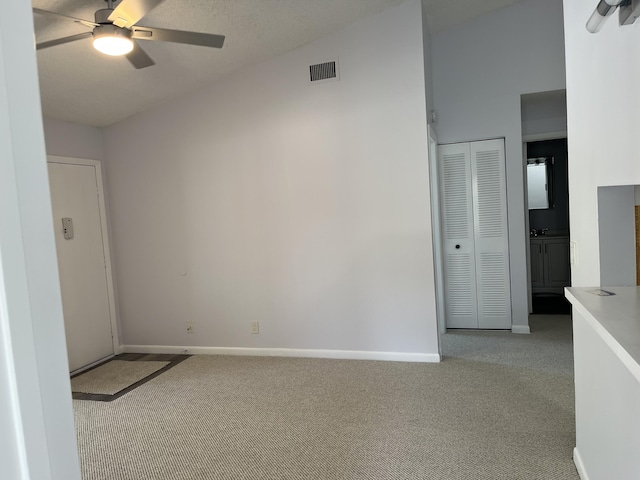 spare room featuring carpet floors, ceiling fan, visible vents, and vaulted ceiling