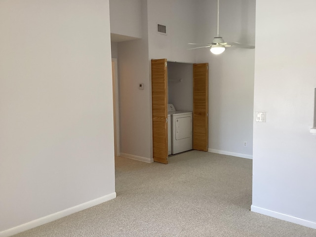 spare room with light carpet, visible vents, baseboards, ceiling fan, and washer / clothes dryer