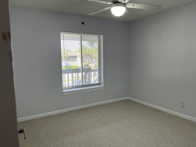 carpeted spare room with ceiling fan and baseboards