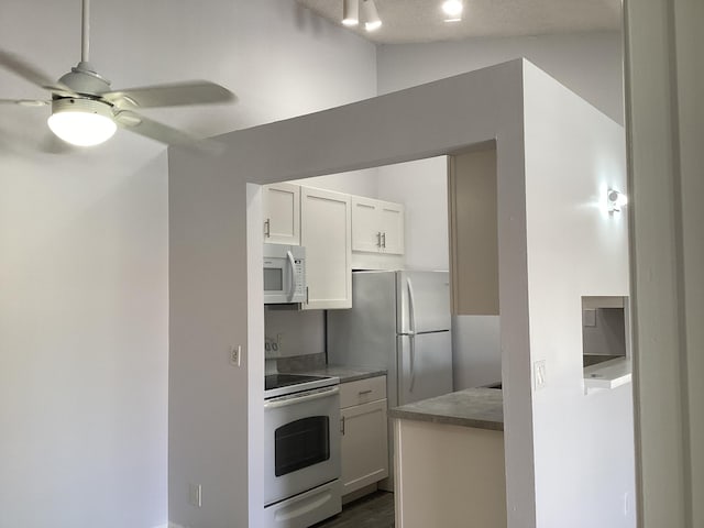 kitchen featuring white appliances, ceiling fan, vaulted ceiling, and white cabinets