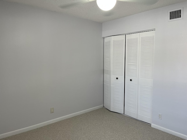 unfurnished bedroom featuring baseboards, a textured ceiling, visible vents, and carpet flooring