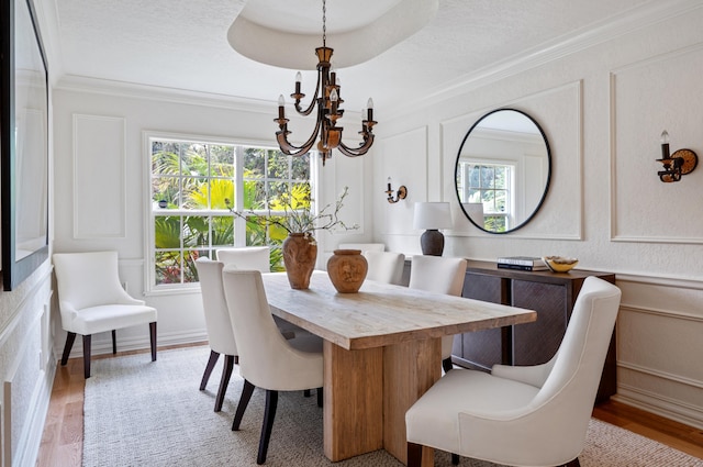 dining space with an inviting chandelier, crown molding, a wealth of natural light, and light hardwood / wood-style floors