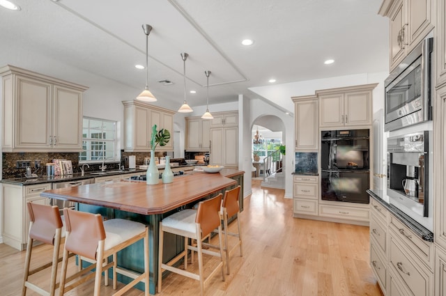 kitchen featuring stainless steel microwave, cream cabinets, and hanging light fixtures