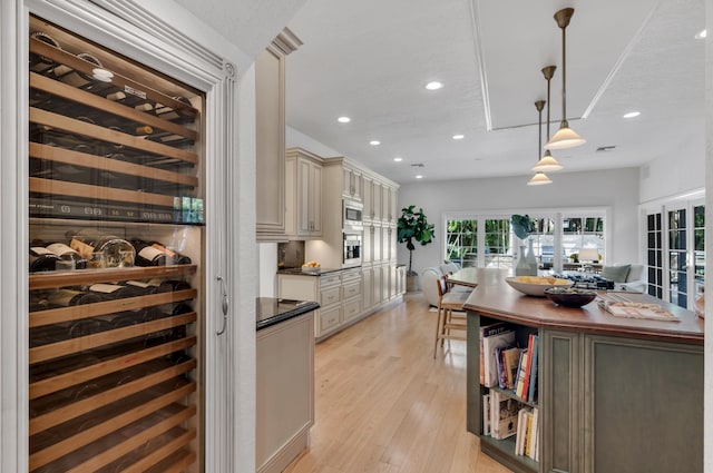 kitchen with wine cooler, decorative light fixtures, light wood-type flooring, stainless steel appliances, and cream cabinetry